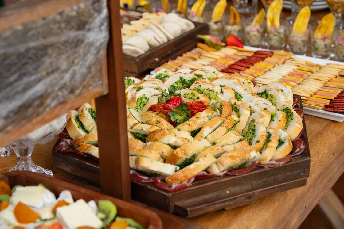 Mesa de buffet com pequenas porções dispostas em travessas de madeira e cerâmica