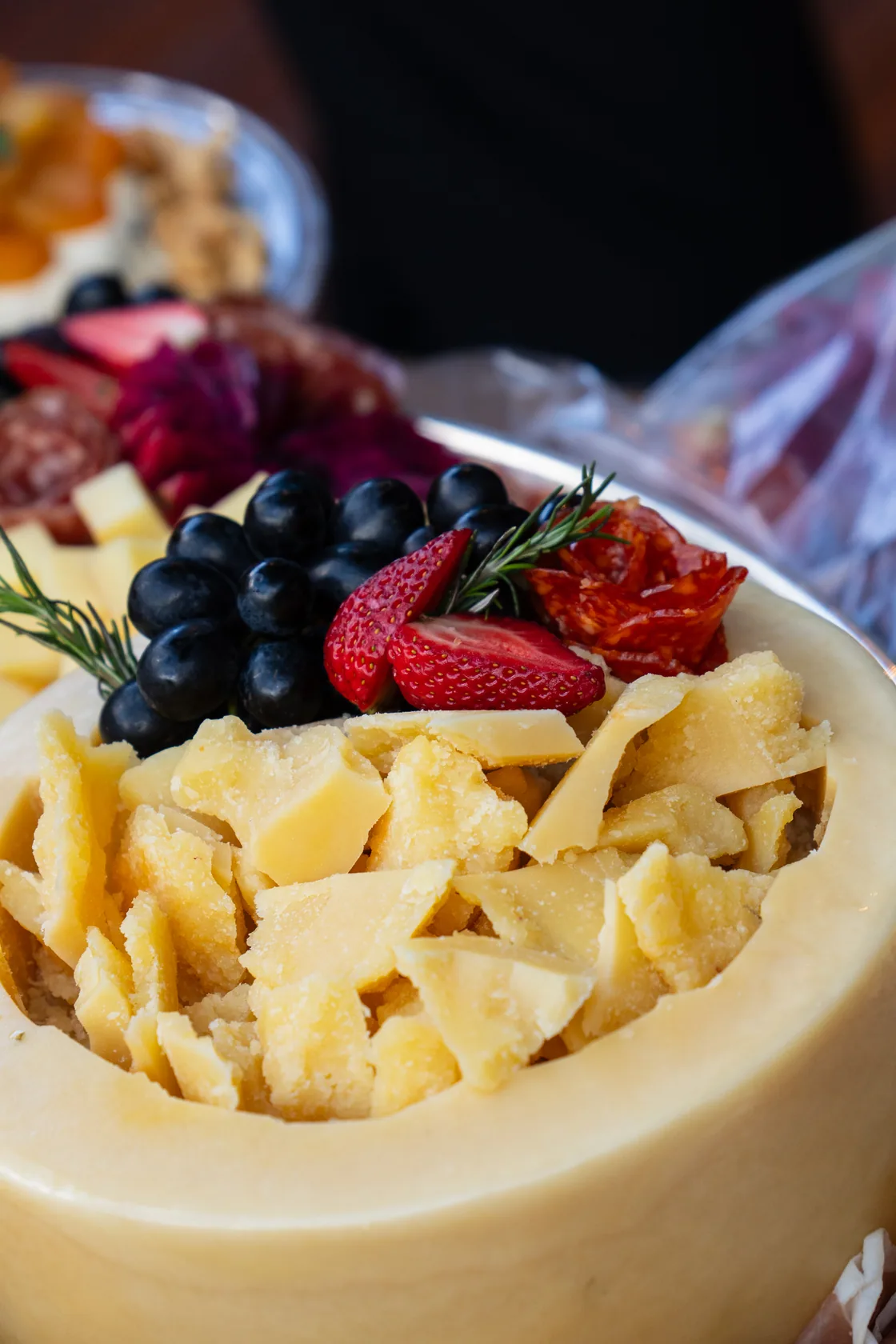 Detalhe de uma composição de queijos, uvas, morangos e frios